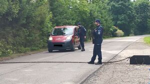 Policjanci stojący przy rozłożonej kolczacce na drodze, zatrzymujący samochód