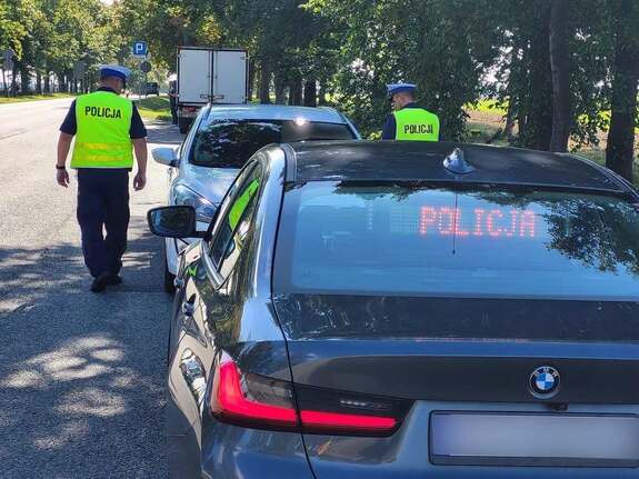 Policjant w kamizelce odblaskowej idący do kontrolowanego pojazdu