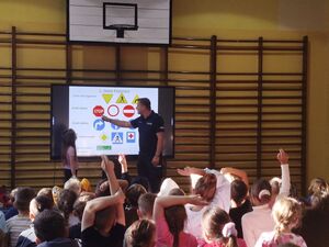 Policjant na sali sportowej podczas spotkania z dziećmi