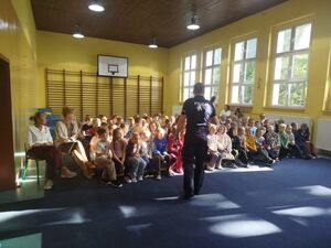 Policjant na sali sportowej podczas spotkania z dziećmi
