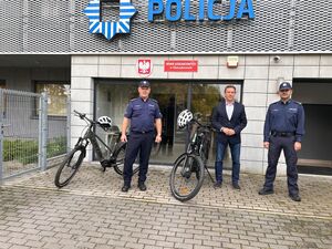Policjanci z rowerami stojący przed budynkiem