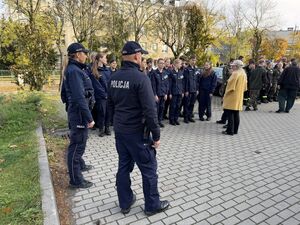 Dwóch policjantów, kobieta i mężczyzna stojących na parkingu podczas zbórki uczniów szkoły mundurowej