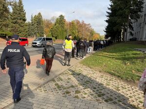 Policjan idący za młodzieżą podczas próbnej ewakuacji szkoły
